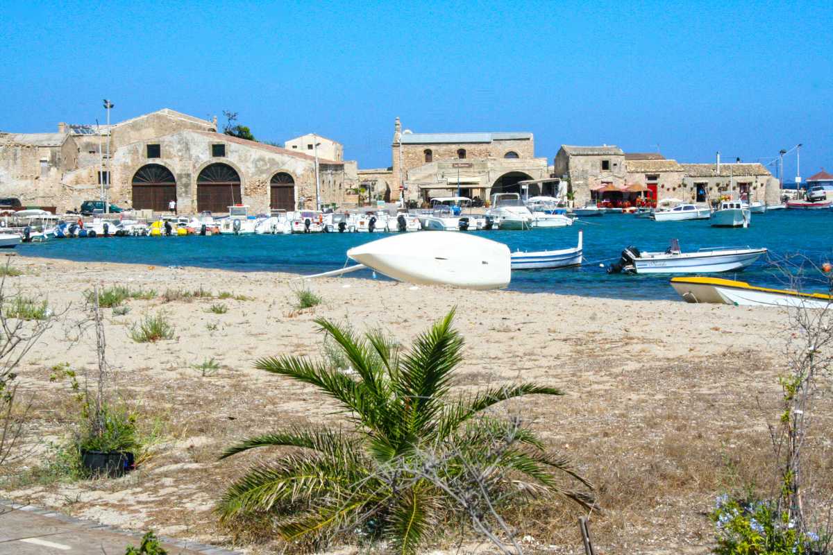 Scorcio panoramico di Marzamemi, con la Tonnara in primo piano e il mare sullo sfondo, atmosfera vivace di giorno